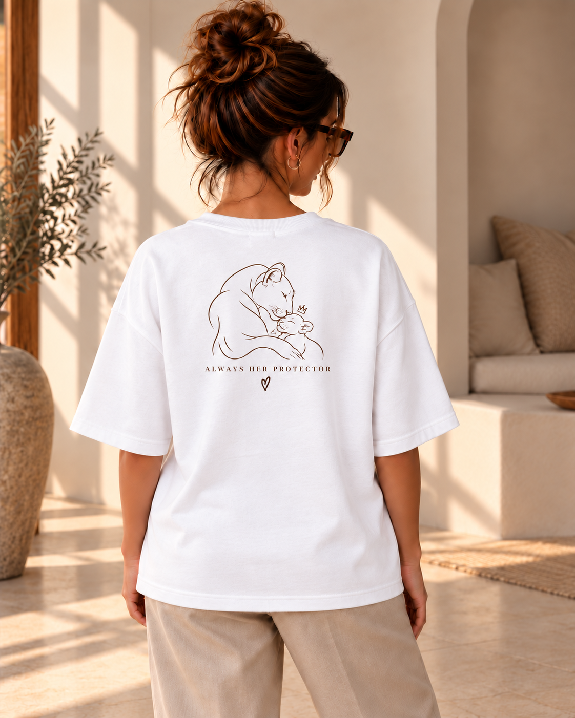 Achteraanzicht van een vrouw in een wit oversized T-shirt met rugprint van een leeuwin met welpje en “ALWAYS HER PROTECTOR”