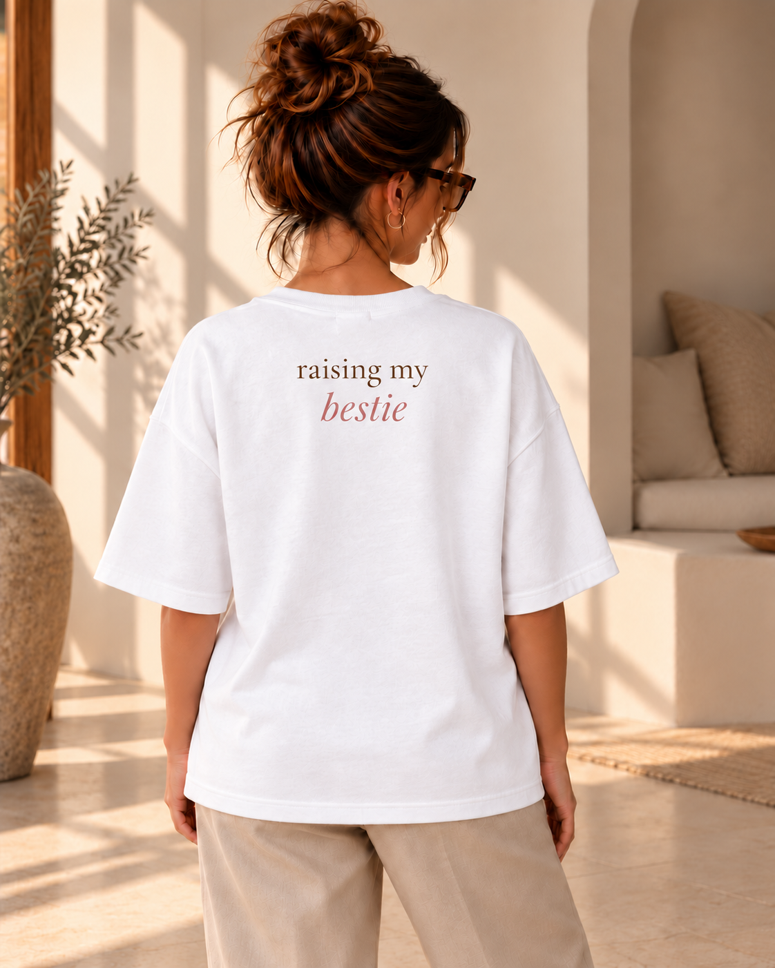 Achteraanzicht van een vrouw in een wit oversized T-shirt met rugprint “raising my bestie”